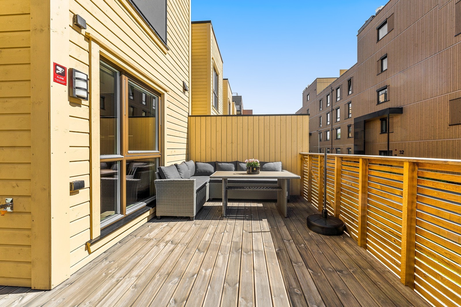 Dette moderne rekkehuset fra 2023 har en stor, sydvendt terrasse med Royal-impregnerte bord og levegg mot nabo. Galleribilde