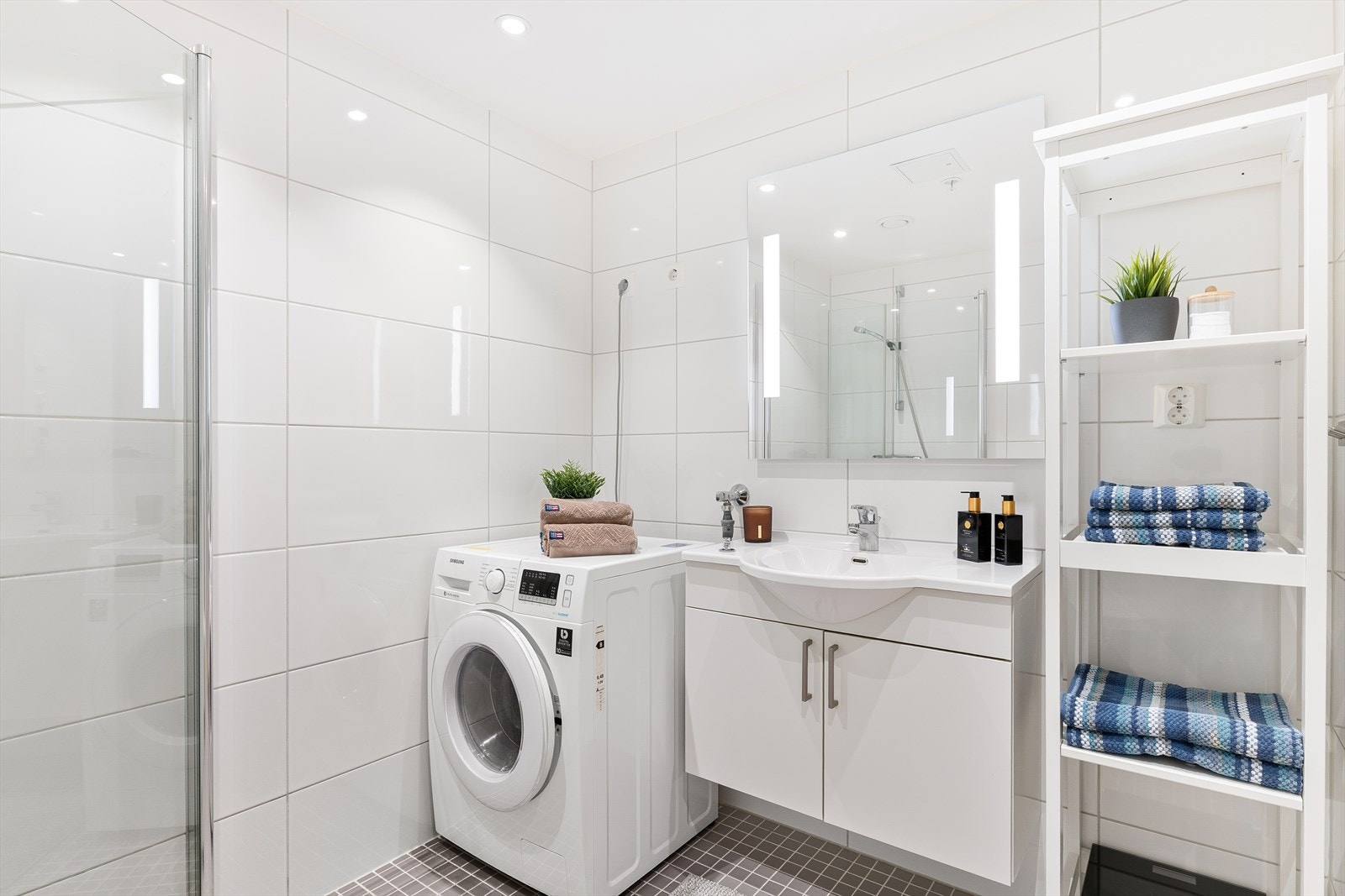 Badet er utstyrt med innfellbare dusjdører, mekanisk avtrekk, toalett, servant i skap, og opplegg for vaskemaskin/tørketrommel. Galleribilde