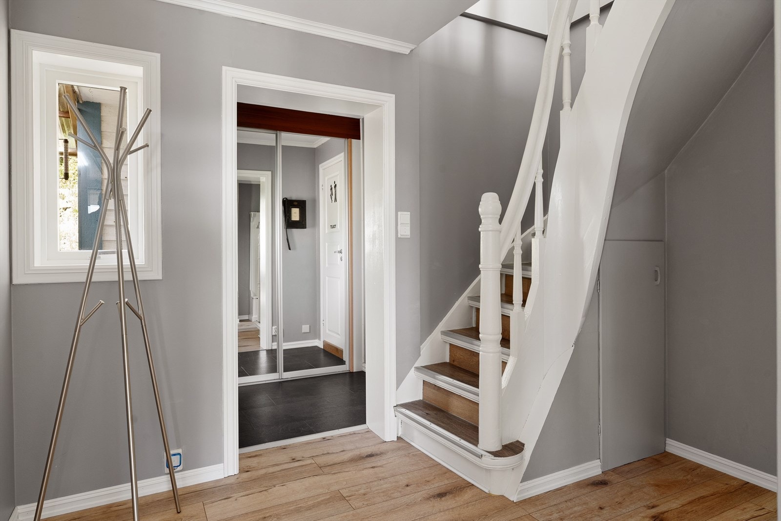 Velkommen inn! Du blir møtt av en lys og trivelig gang med gode oppbevaringsmuligheter i skyvedørsgarderobe med speil Galleribilde