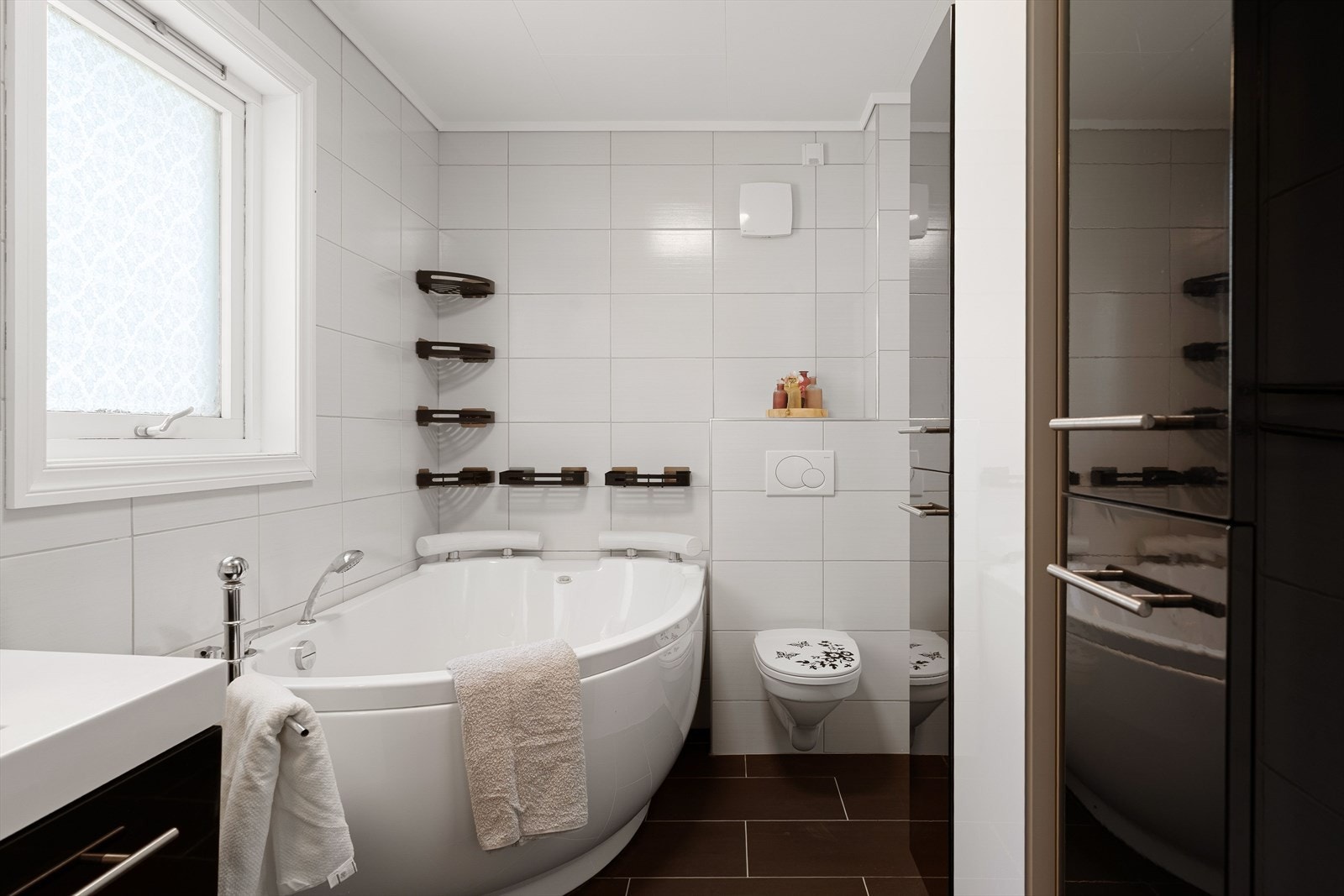 Badet er innredet med servant i møbel, vegghengt toalett, badekar og høyskap Galleribilde