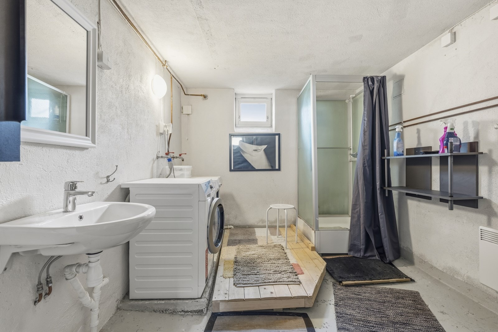 Praktisk vaskerom i kjelleren med malte murvegger, opplegg for vaskemaskin og dusjkabinett. Galleribilde
