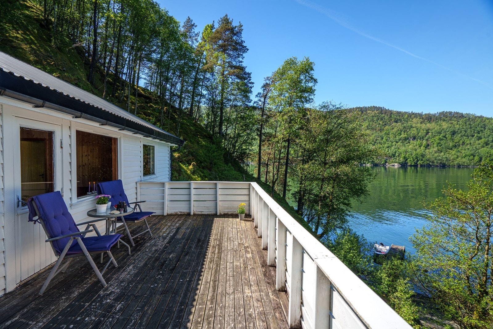 Terrasse som strekker seg langs hyttas fasade mot sjøen. Galleribilde