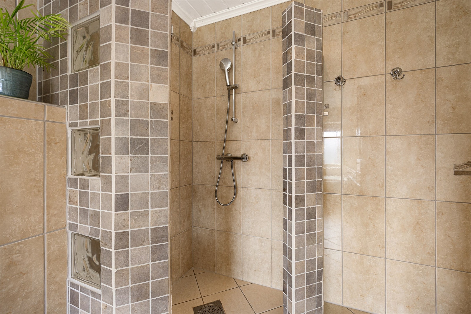 I tillegg til badekar har badet en separat dusjnisje med flislagte vegger. Galleribilde