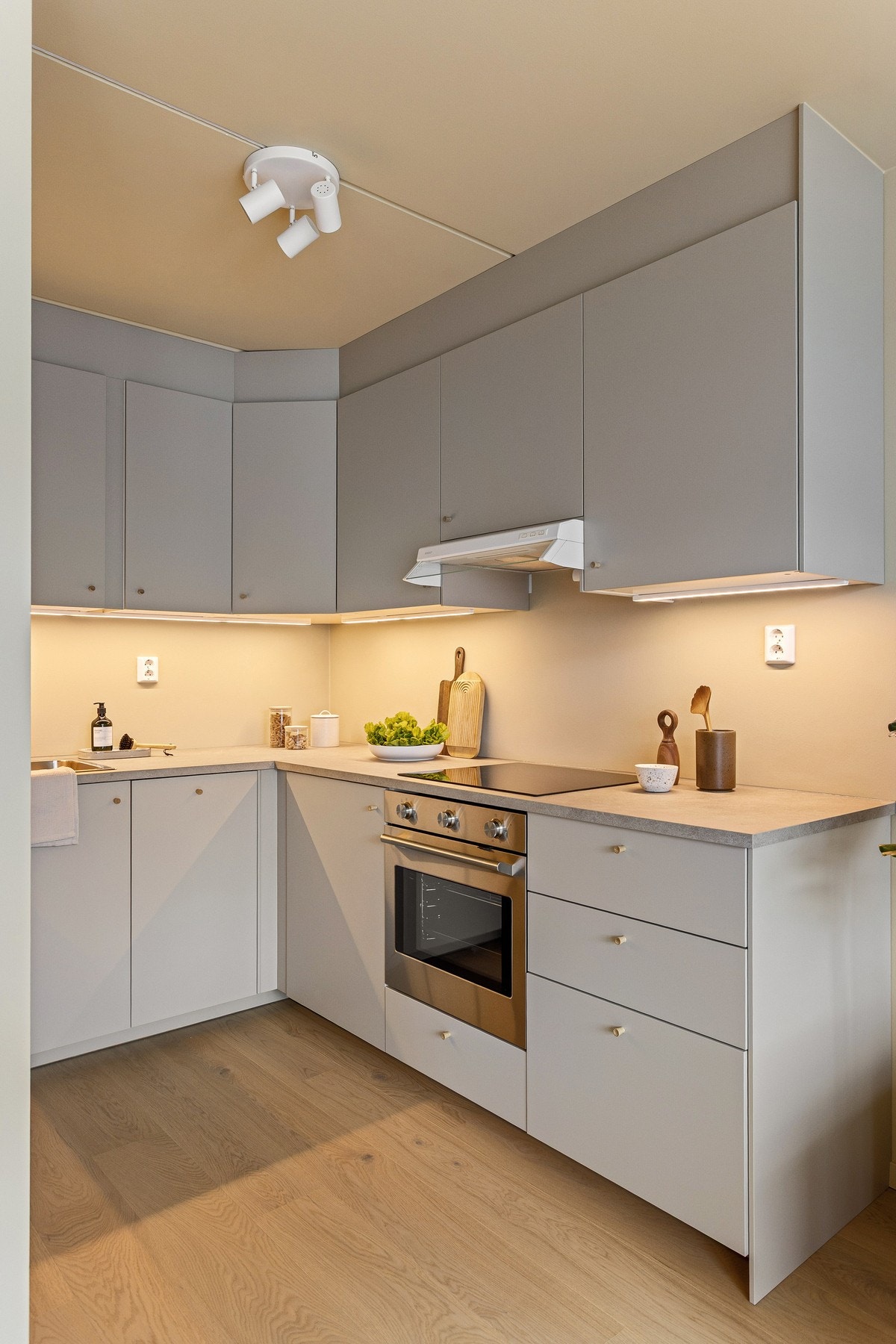 Grå, glatt innredning med laminat benkeplate og planlimt kum i rustfritt stål med ett-greps armatur. Galleribilde