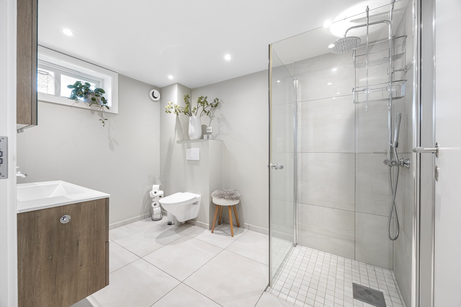 Badet har vegghengt toalett, servantinnredning og dusjhjørne. Vaskerommet har praktisk arbeidsbenk, utslagsvask og overskap. Galleribilde