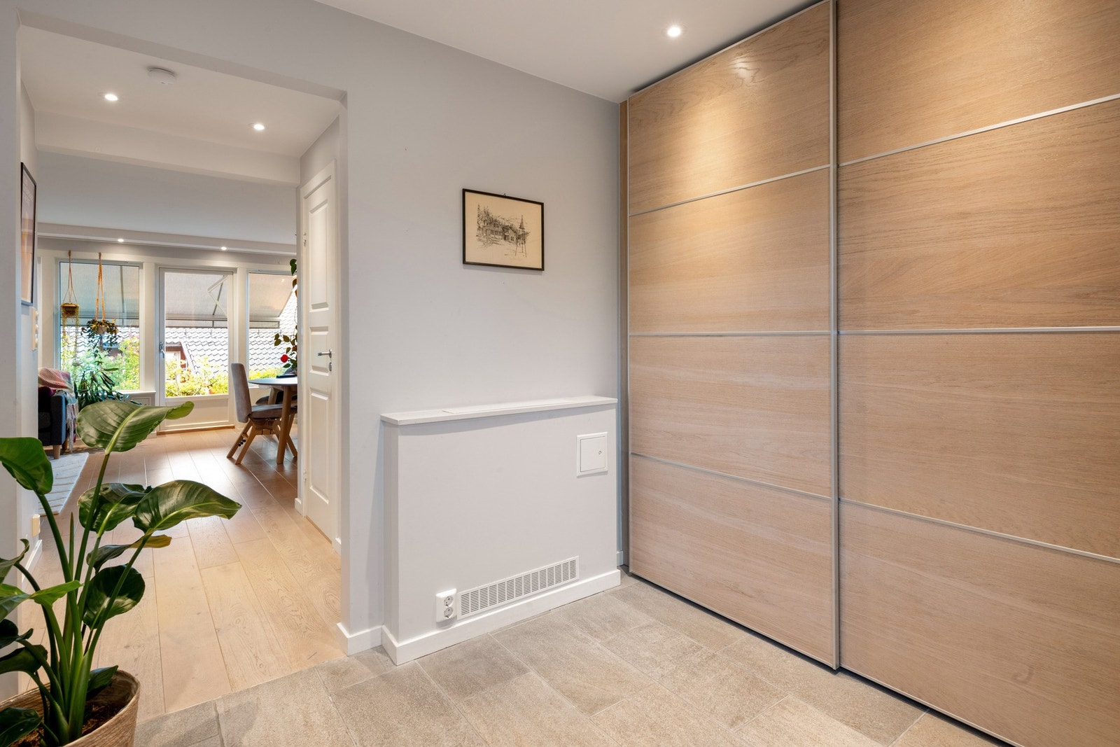 Entreen har flislagt gulv med gulvvarme, helsparklede og malte vegger. Stor skyvedørsgarderobe langs den ene veggen. Innkasset radiator med fjernvarme. Stue og kjøkken har lik enstavsparkett. Galleribilde
