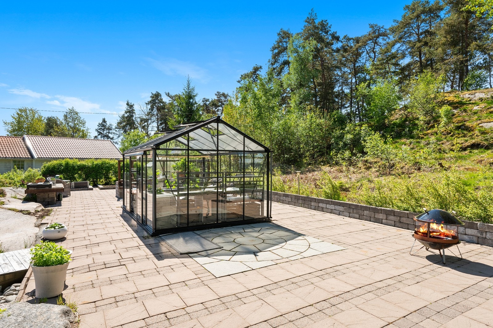 En stor, hellelagt uteplass omkranser det store drivhuset. Galleribilde