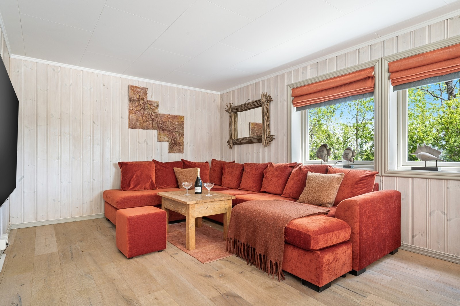 Overflatene i stuen består av parkett på gulv og lyst trepanel på vegger. Galleribilde