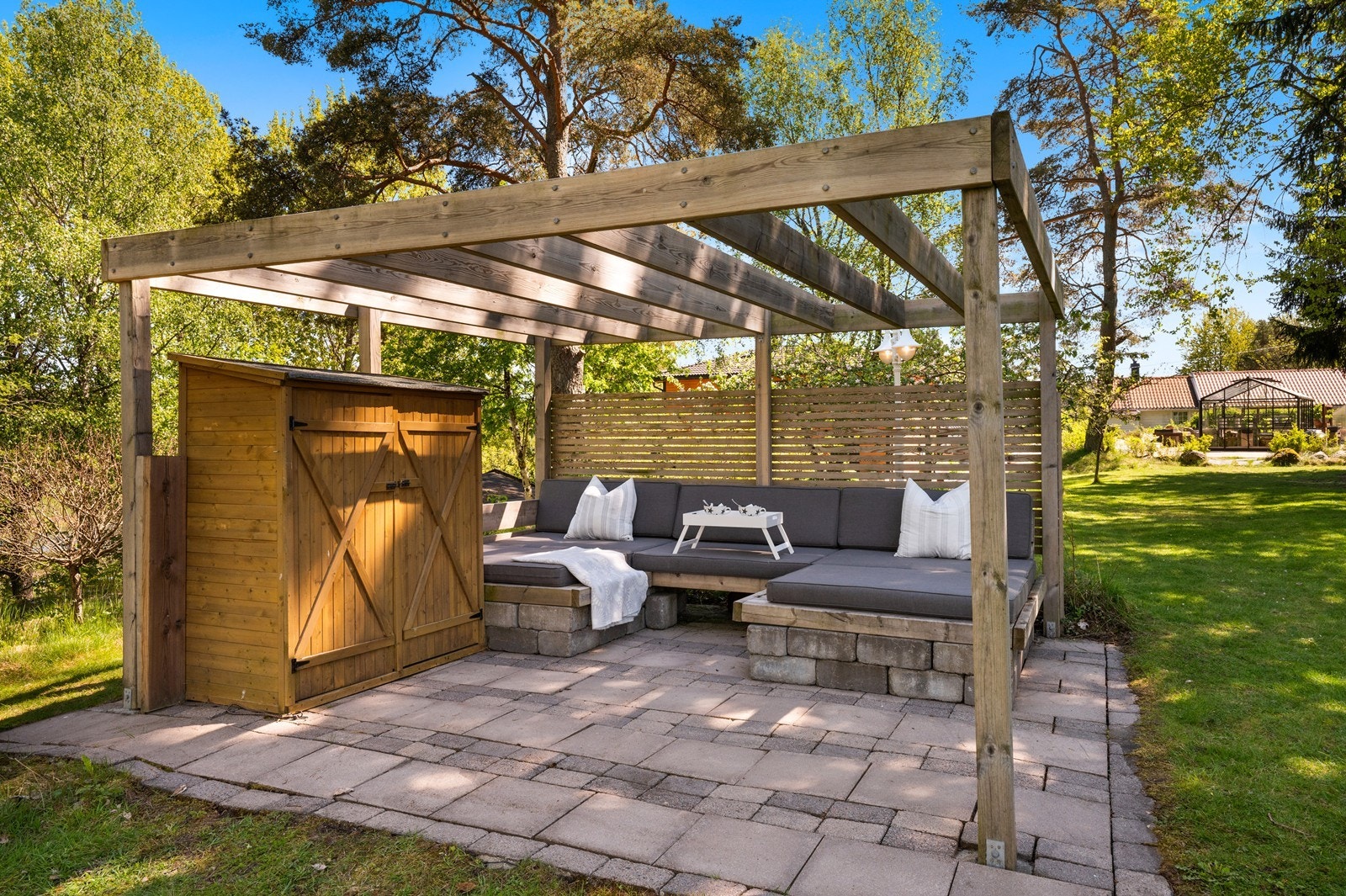 En egen sone i hagen med pergola og fastmontert sittegruppe. Galleribilde