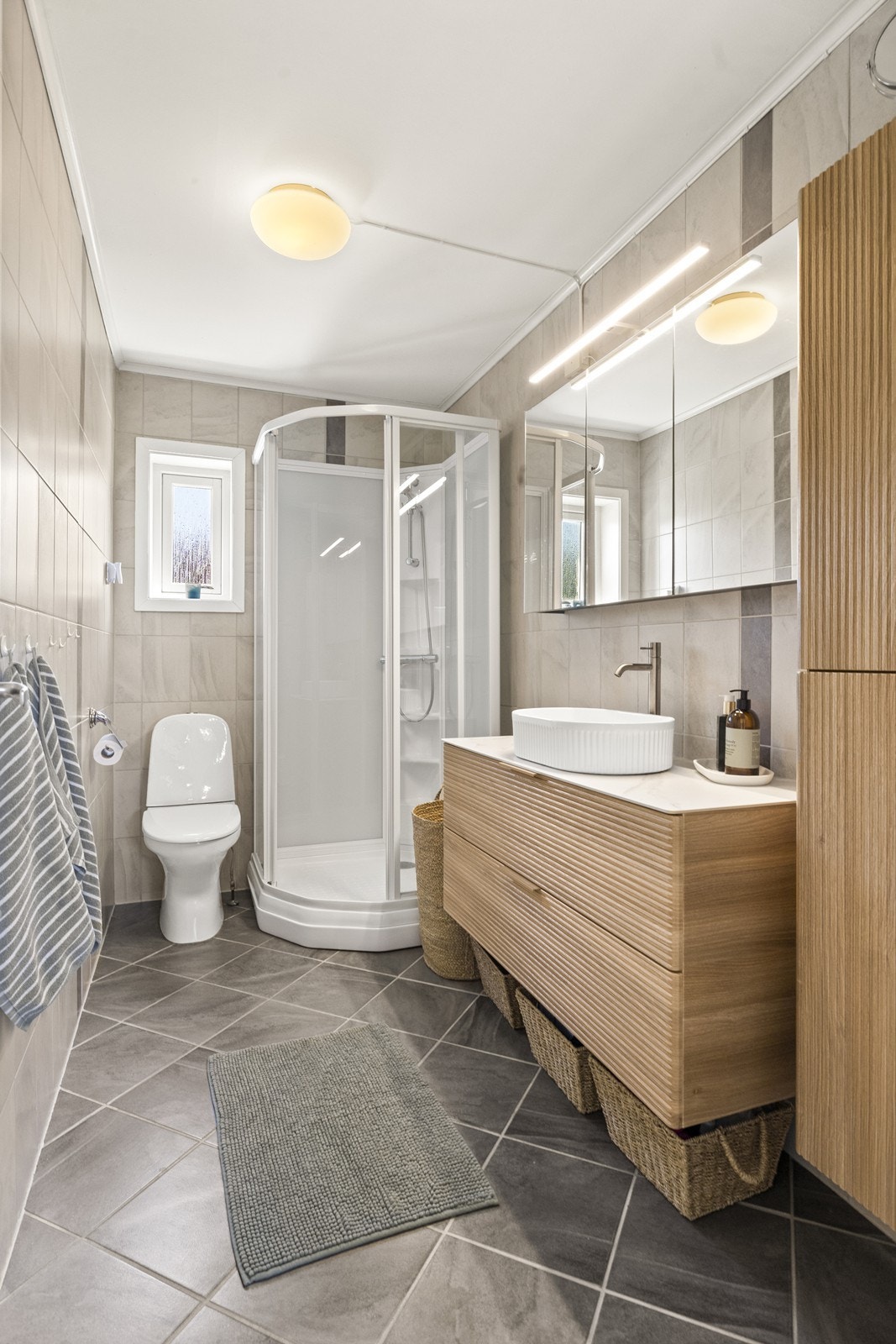 Badet i første etasje har flislagt gulv med varmekabler. Innredning og dusjkabinett ble montert i 2026. Galleribilde
