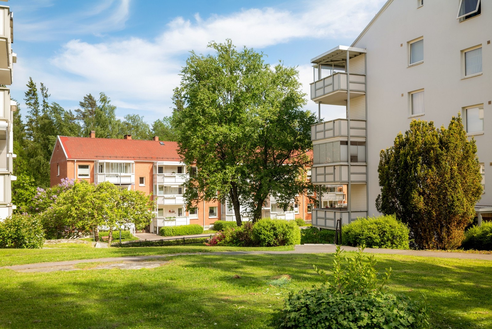 Tomten er svært pent opparbeidet med store grøntområder, frodig beplantning, hyggelige sittegrupper og lekeplasser Galleribilde