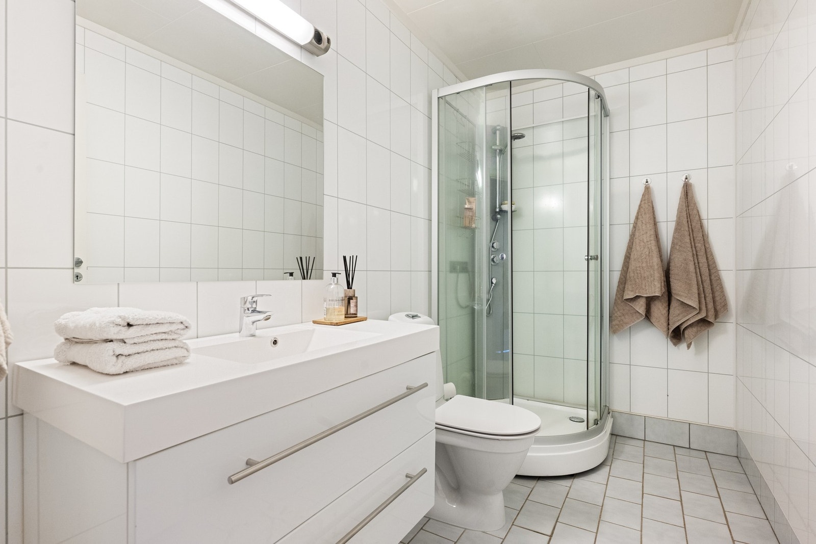 Badet er innredet med flislagt gulv og baderomsplater på veggene. Galleribilde