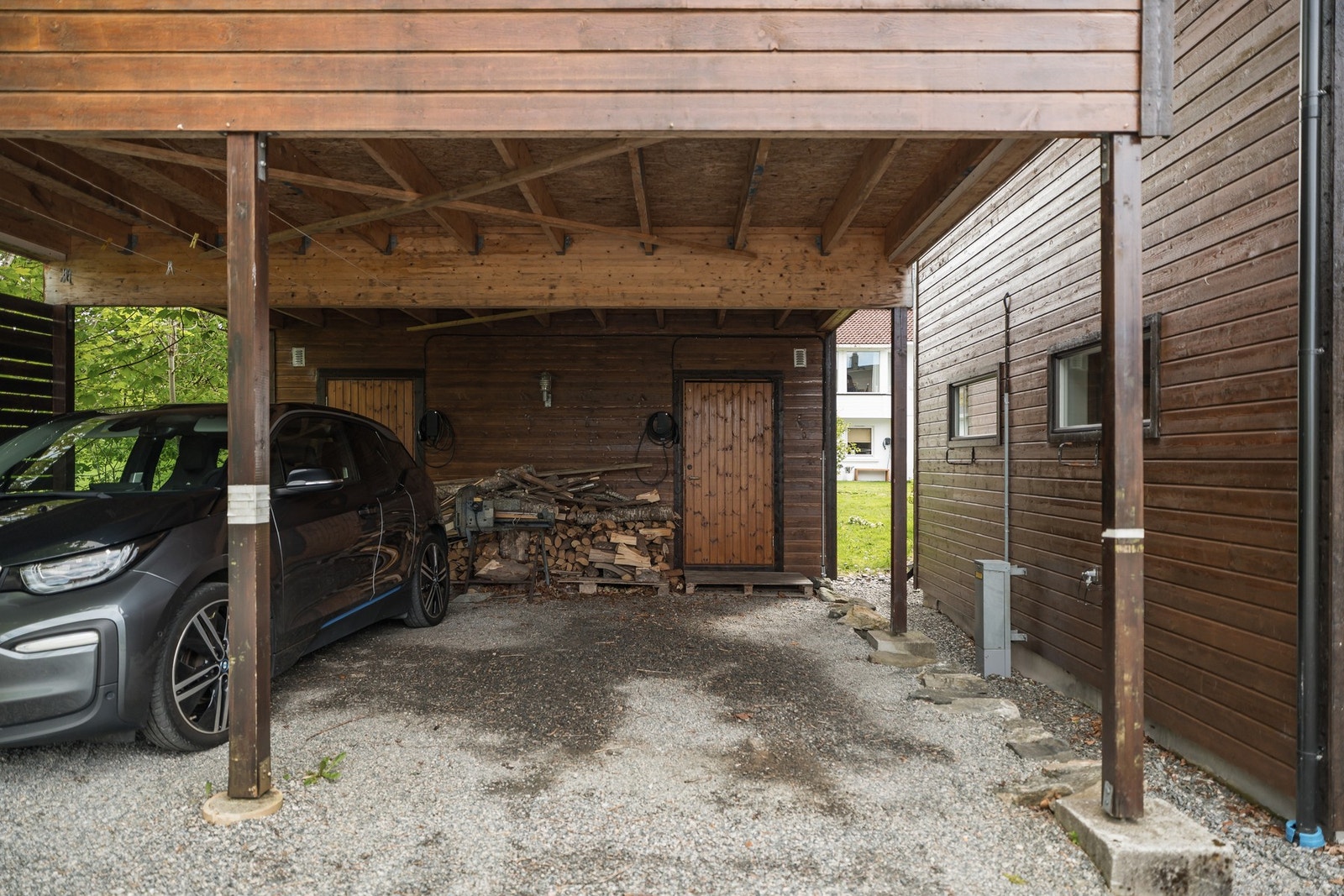 Boligen disponerer carportplassen til høyre, med installert elbillader i 2026. Galleribilde