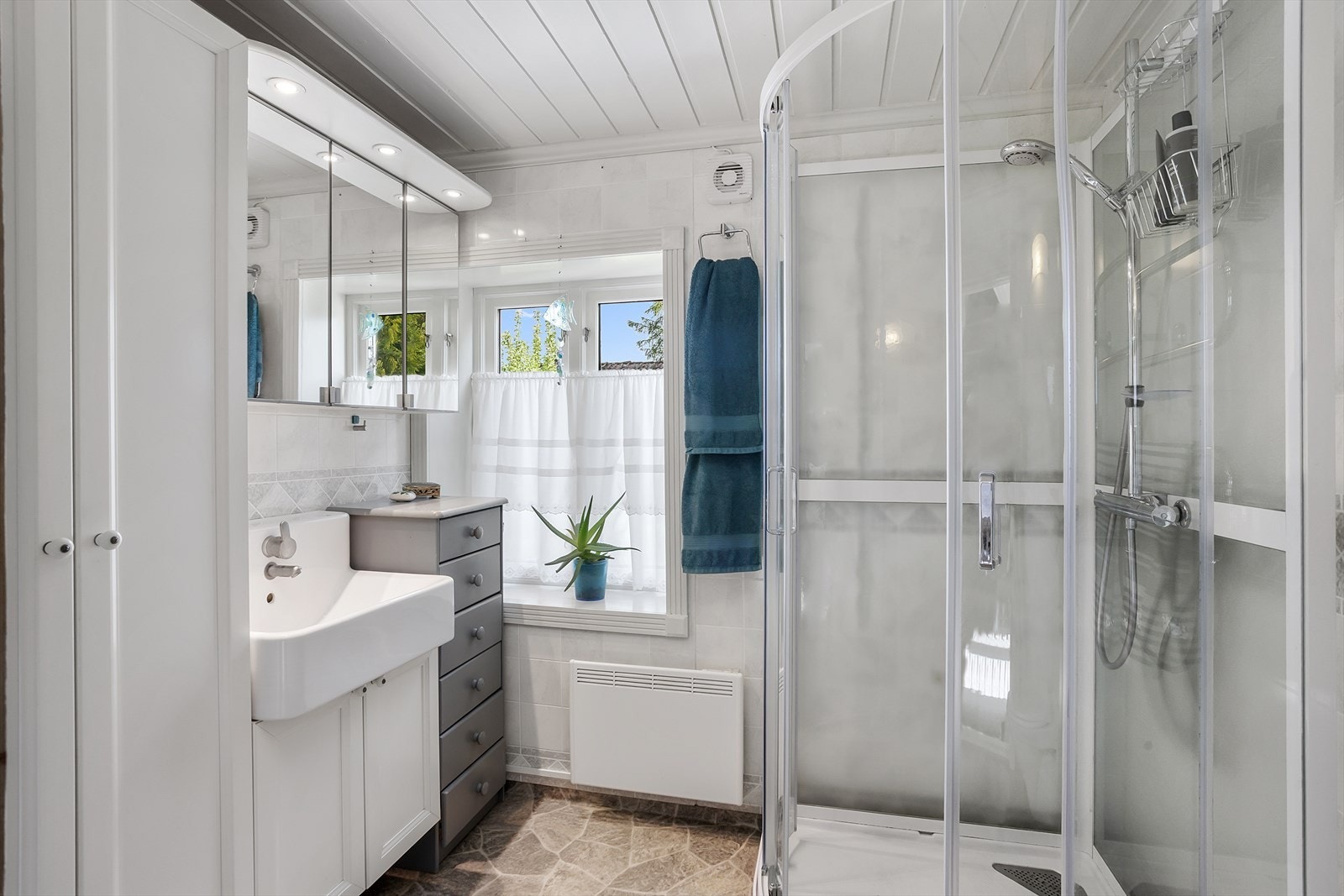 Badet er fra 1995. Innredningen består av nedfelt servant, veggmontert toalett og dusjkabinett fra 2017. Det er opplegg for vaskemaskin. Galleribilde