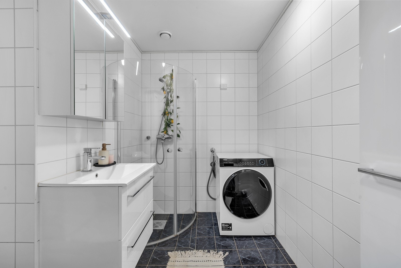 Boligen har ett pent bad med dusjhjørne, wc, opplegg til vaskemaskin og servant med over/underskap. Galleribilde