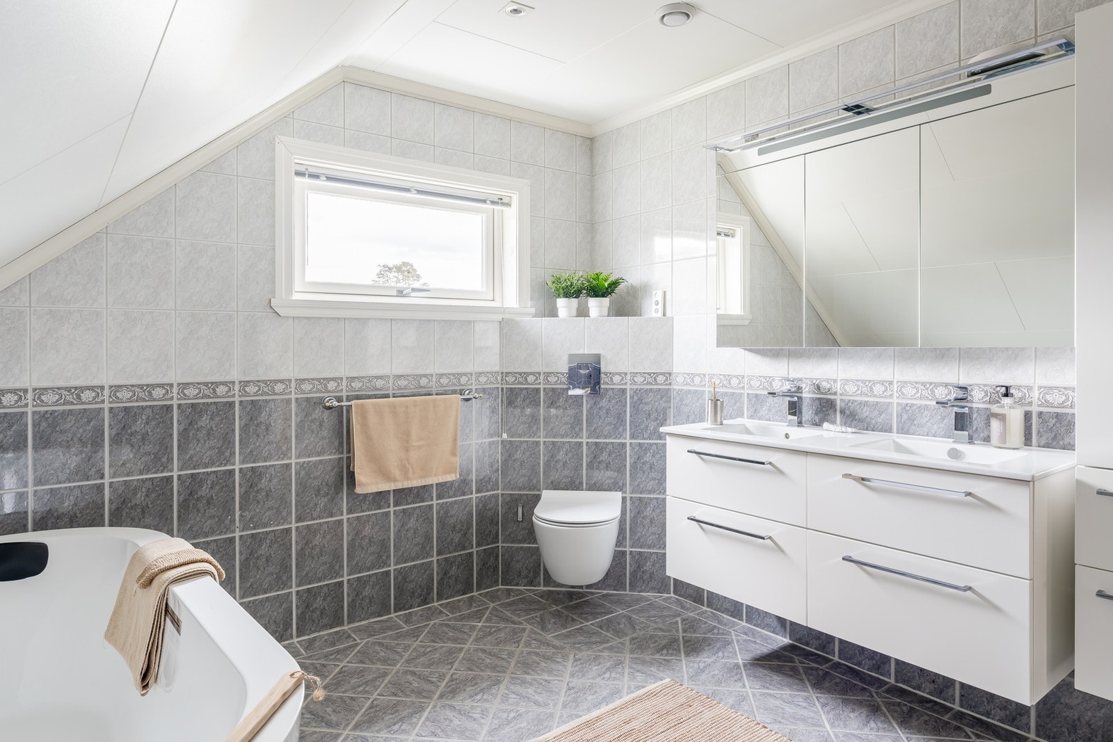Badet er innredet med vegghengt toalett, skuffeinnredning
med dobbelt overliggende servant, badekar og dusj. Galleribilde