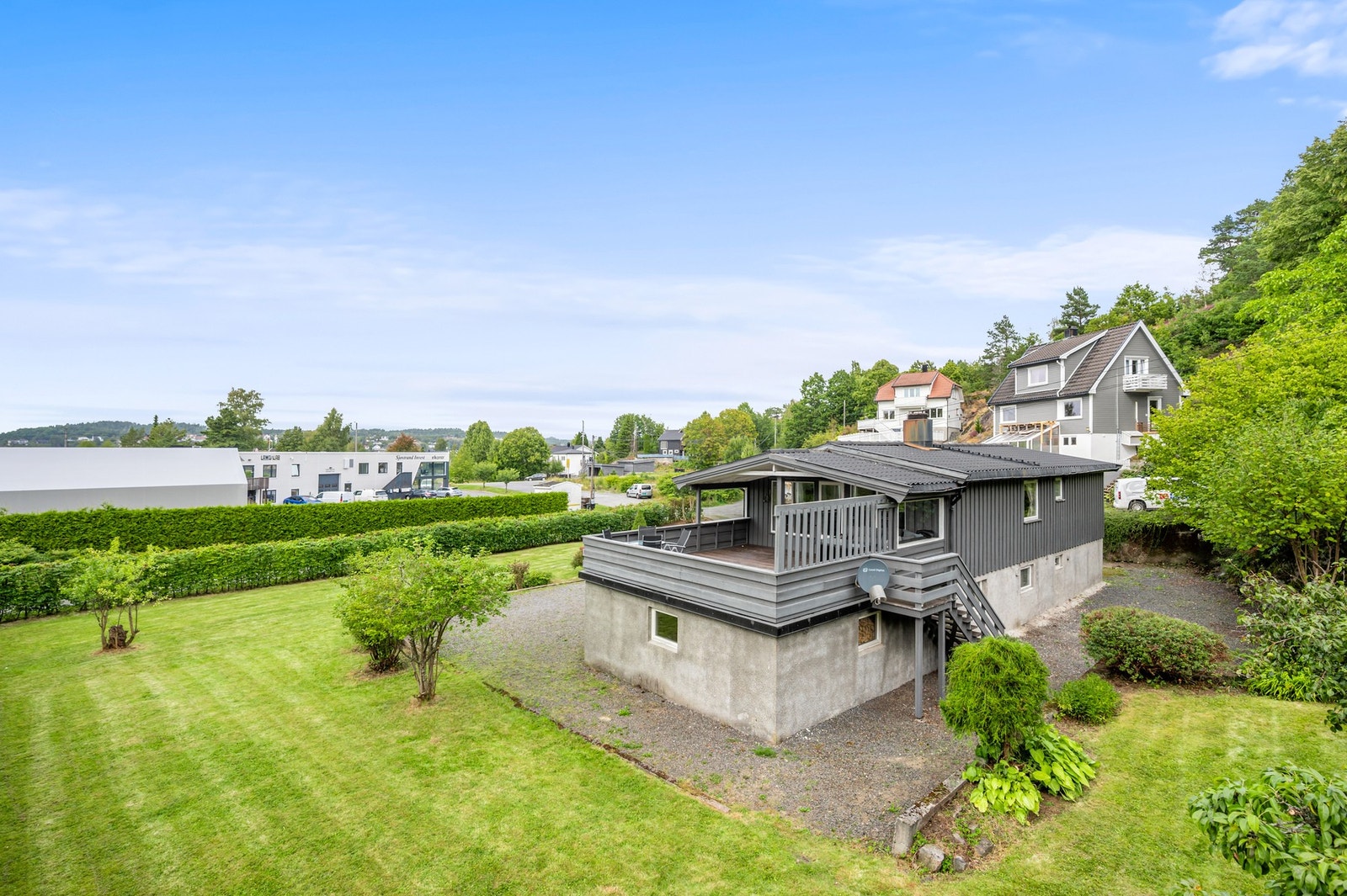 Oversiktsbilde av eiendommen med hage, terrasse og nærliggende området. Galleribilde