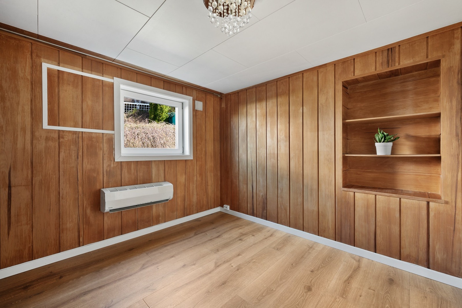 Disponibelt rom i underetasjen med panelte vegger og vindu. Galleribilde