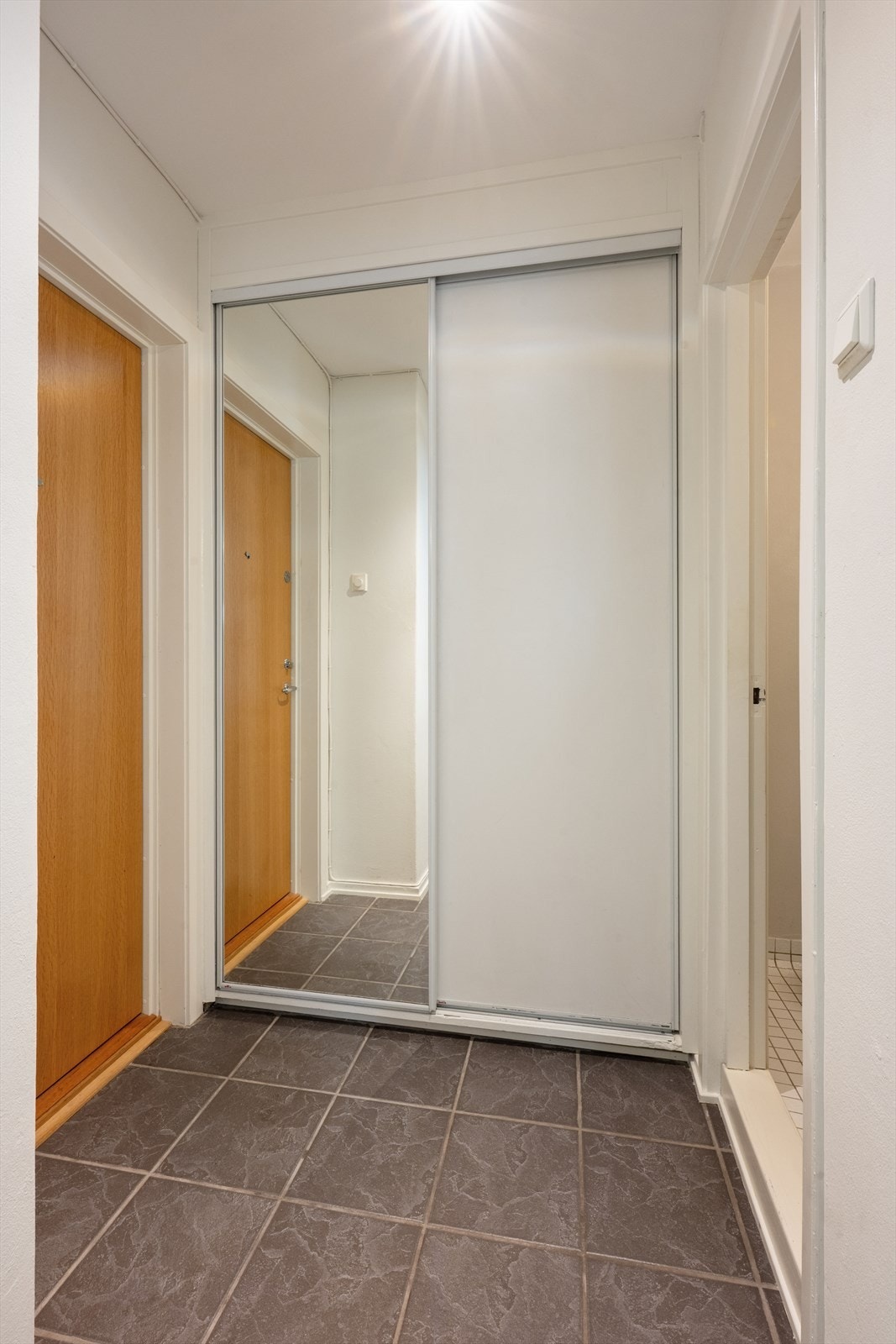 Lys og innbydende entré med skyvedørsgarderobe for oppbevaring av klær og sko. Det er lagt opp til strøm til fryser i garderobeskapet. Galleribilde