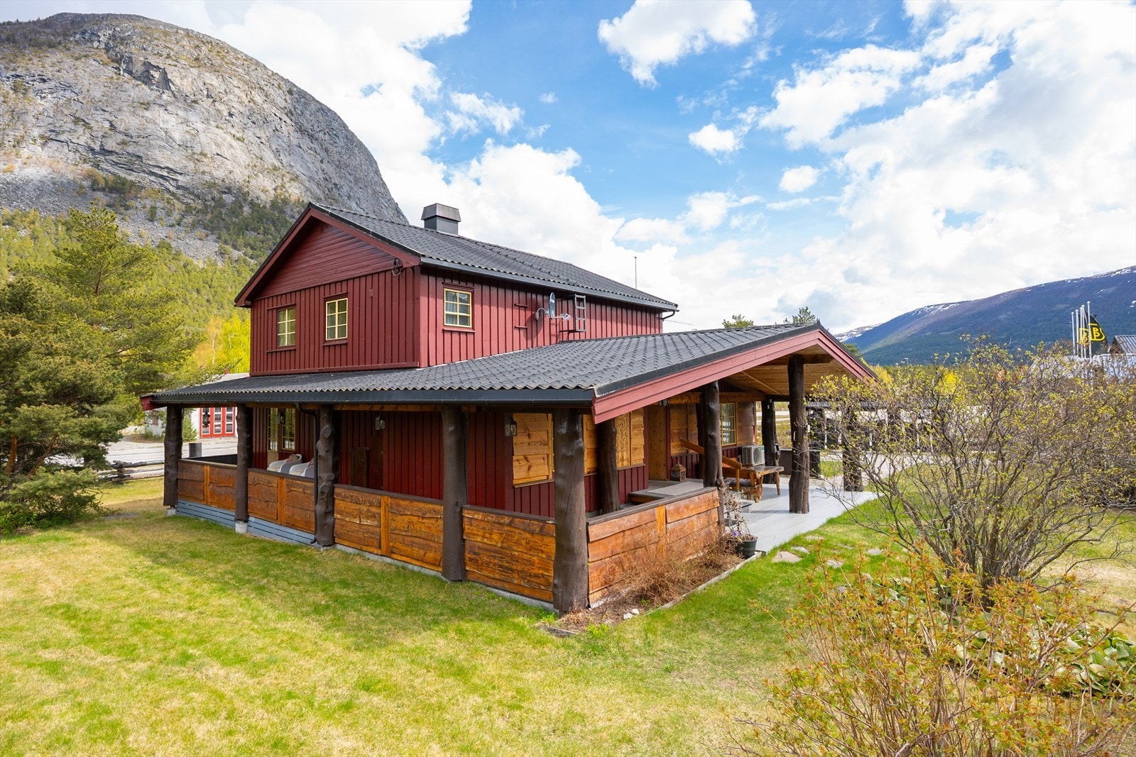 Hovedhuset sett fra siden, med hage og fjellene i bakgrunnen. Galleribilde