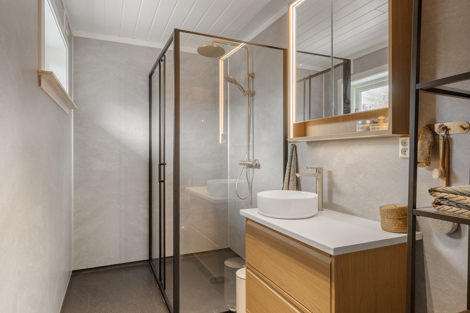 Rommet er utstyrt med dusjhjørne med glassdører og en stilren baderomsinnredning. Badet er nytt fra grunnen av i 2025. Galleribilde