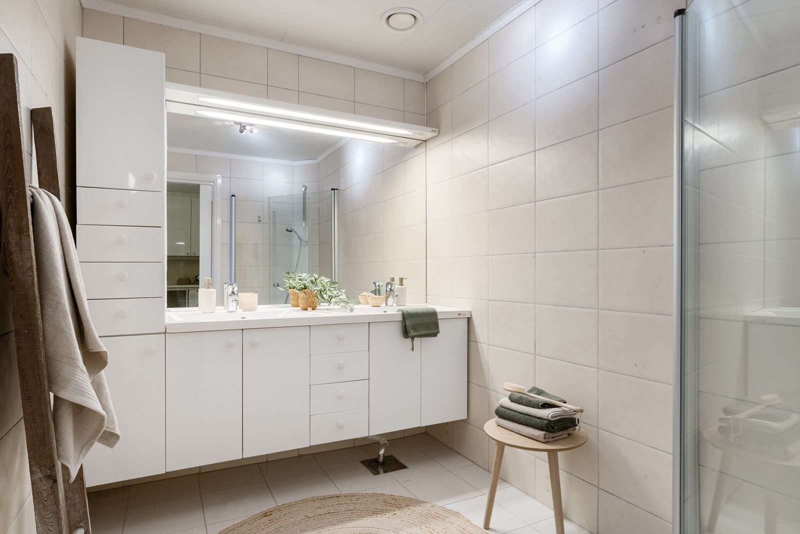 Badet er innredet med servantskap med dobbel servant og tilhørende innredning, samt veggmontert dusjløsning med skjermdører. Galleribilde