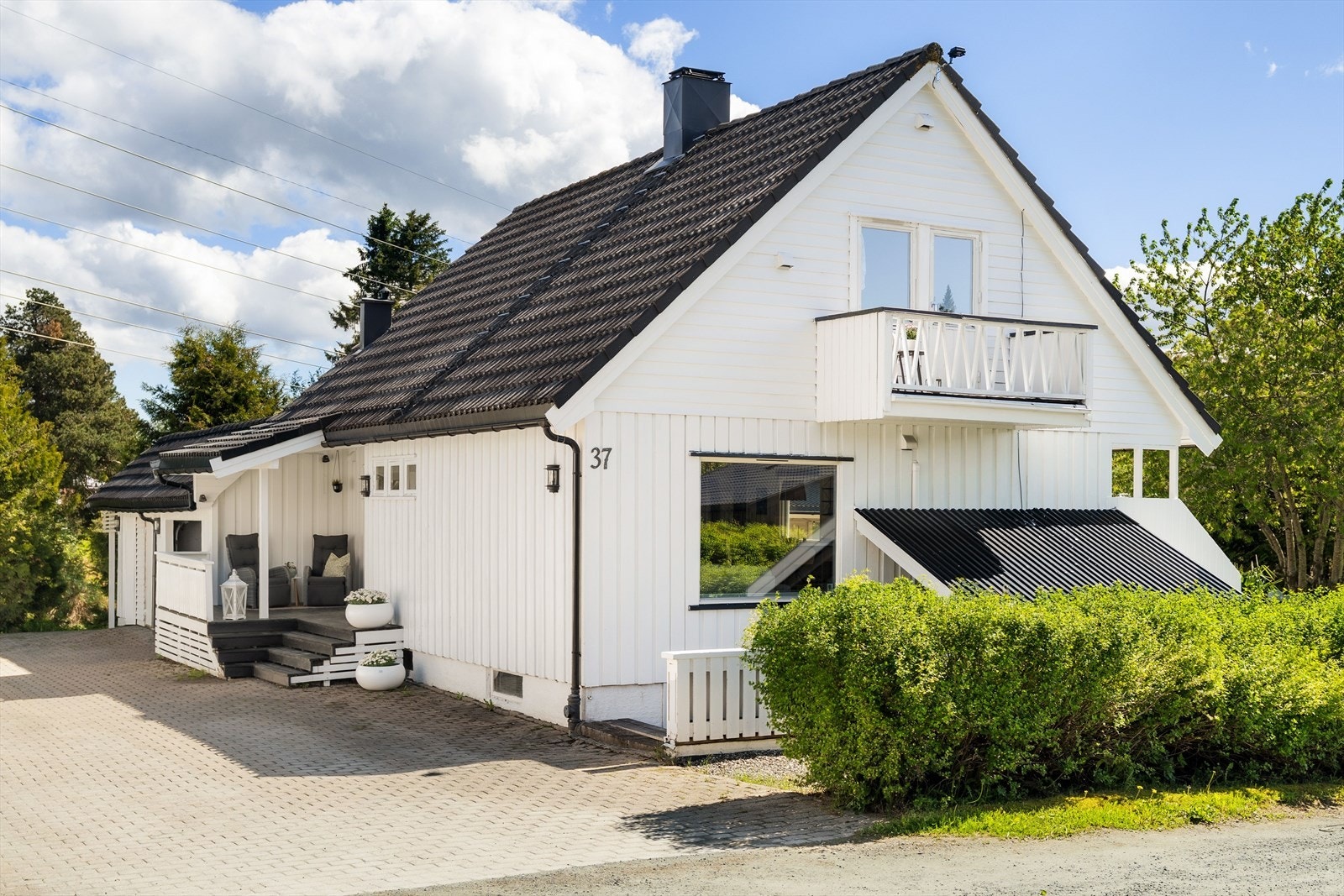 Steinlagt gårdsplass med garasje og bodareal ved garasjen. Kjelleren har egen inngang. Galleribilde