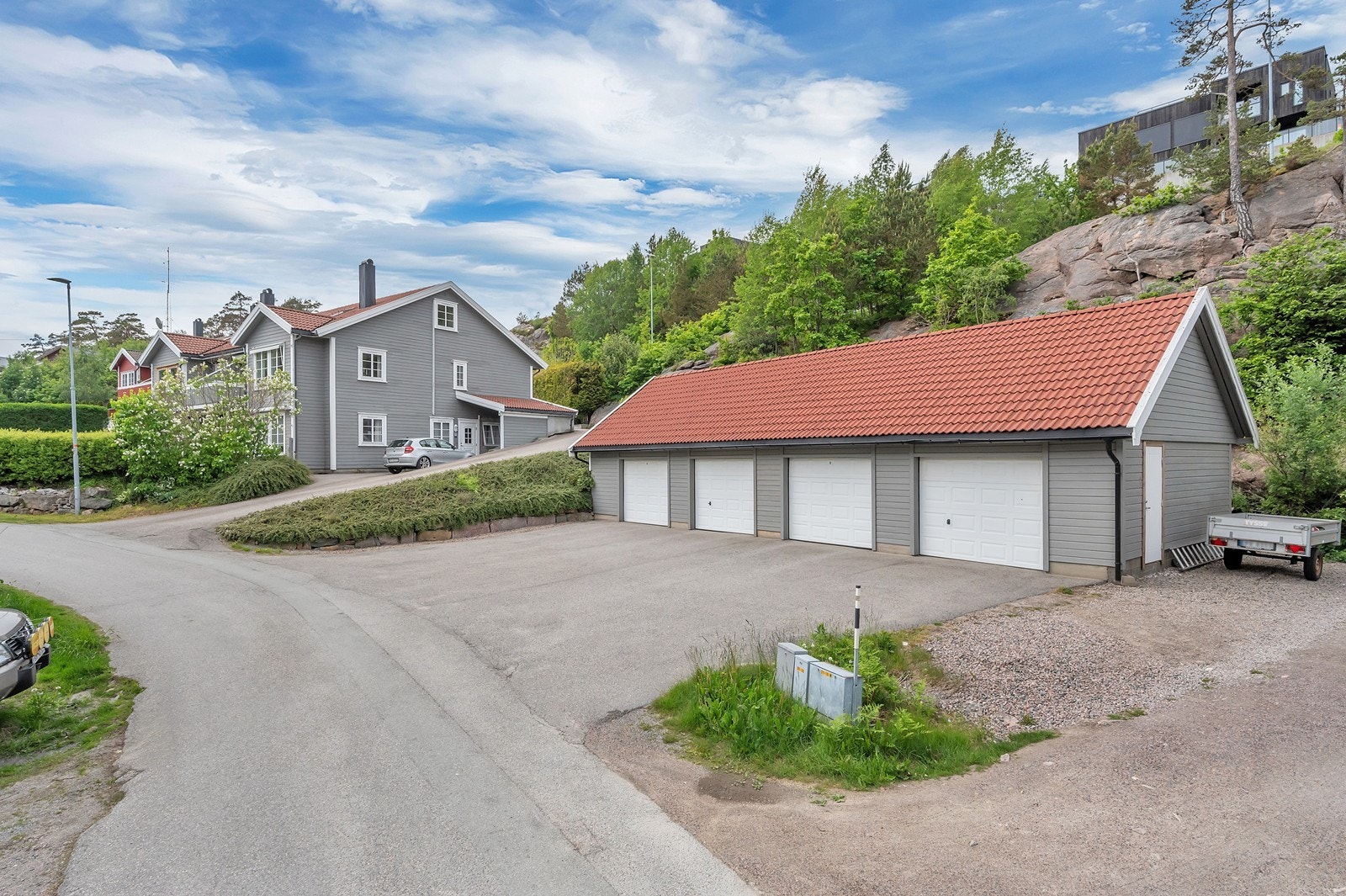 Leiligheten har egen garasje i rekke med loft for lagringskapasitet (helt til venstre). Med biloppstillingsplass foran er det rikelig med parkering. Galleribilde