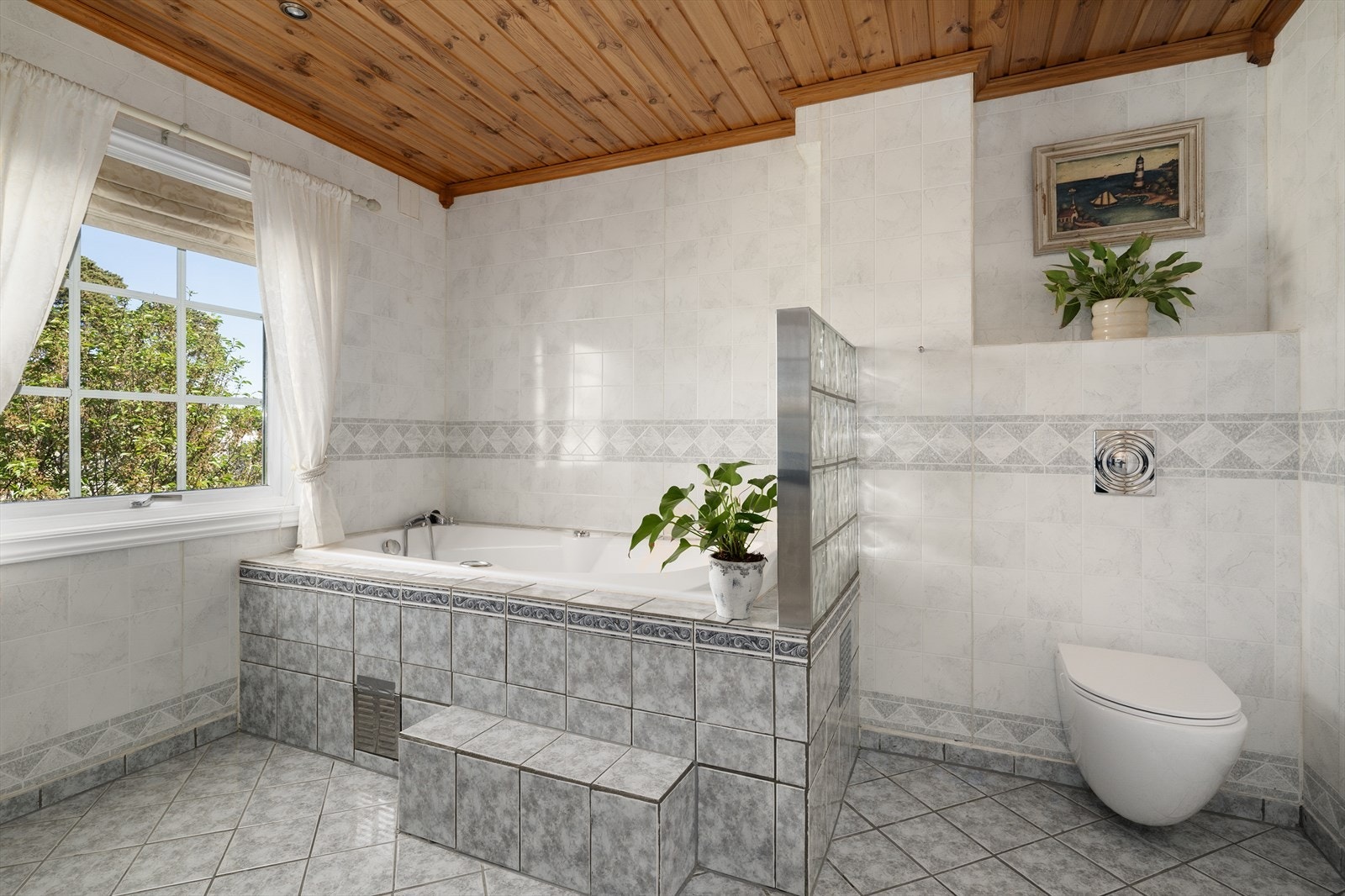 Badet er utstyrt med vegghengt toalett, og veggene er kledd med baderomsplater. Galleribilde