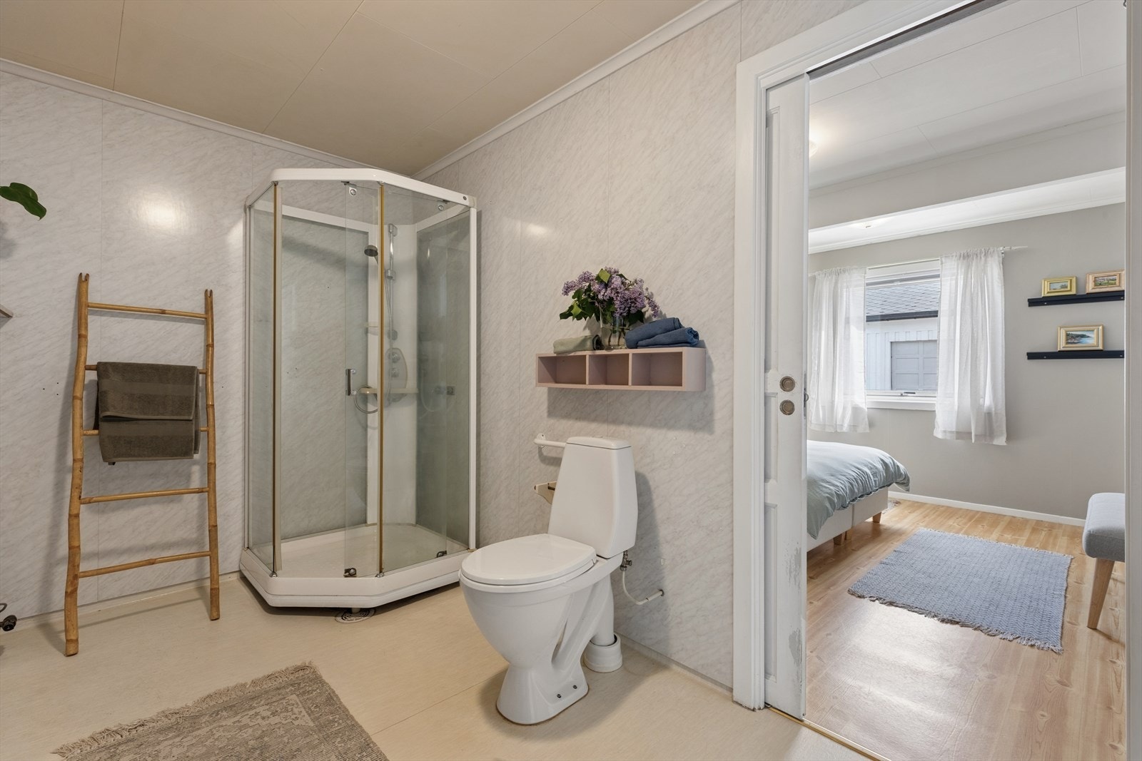 Badet er innredet med servant med underskap, speil med tilhørende belysning, dusjkabinett, gulvmontert toalett, varmtvannsbereder og opplegg for vaskemaskin. Galleribilde