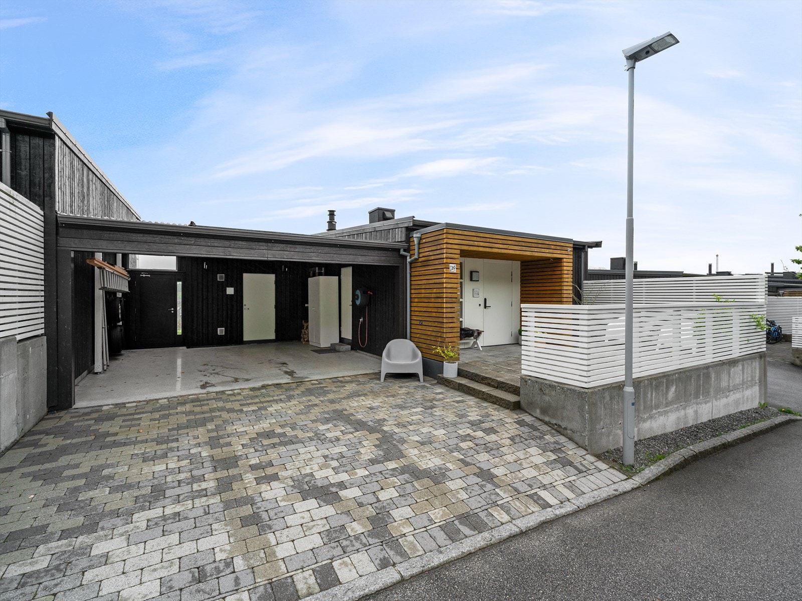 Steinbelagt gårdsrom og dobbel carport med bod i bakkant. Galleribilde