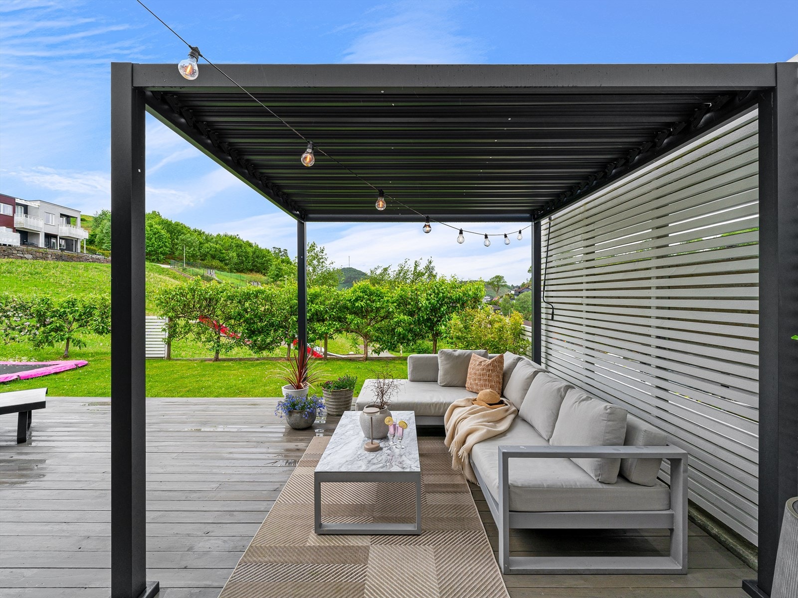 Den store terrassen er pent opparbeidet med flere soner, inkludert en pergola som gir en lun og skjermet uteplass. Galleribilde