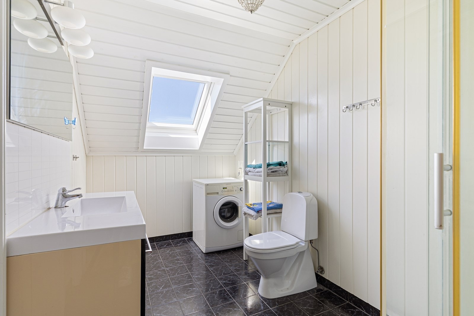 Badet i 2. etasje har adkomst fra gangen. Rommet er innredet med servantinnredning, toalett, dusjkabinett og opplegg for vaskemaskin. Galleribilde