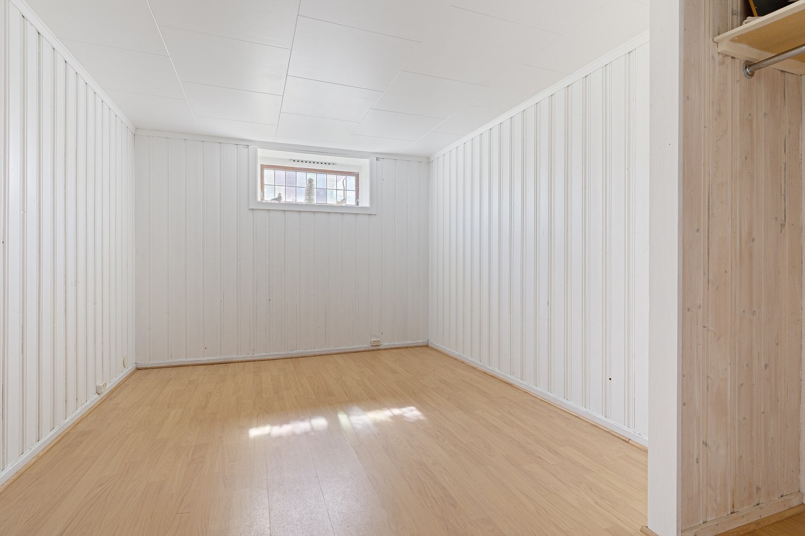 Innredet rom i kjelleren med laminatgulv og panelte vegger. Rommet er ikke godkjent for varig opphold. Galleribilde