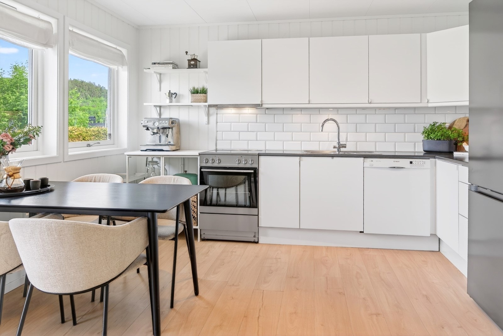 Kjøkkeninnredning med glatte fronter, laminatbenkeplate og hvitevarer som komfyr og oppvaskmaskin. Galleribilde
