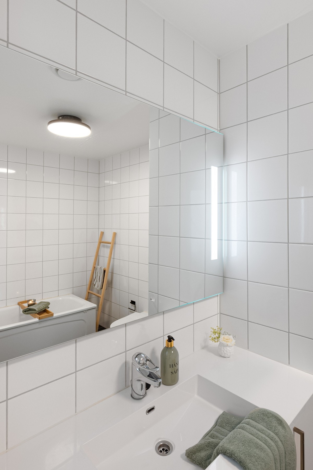 Rommet er innredet med nedfelt servant i hvitt servantmøbel, veggmontert toalett, badekar og opplegg for vaskemaskin. Galleribilde
