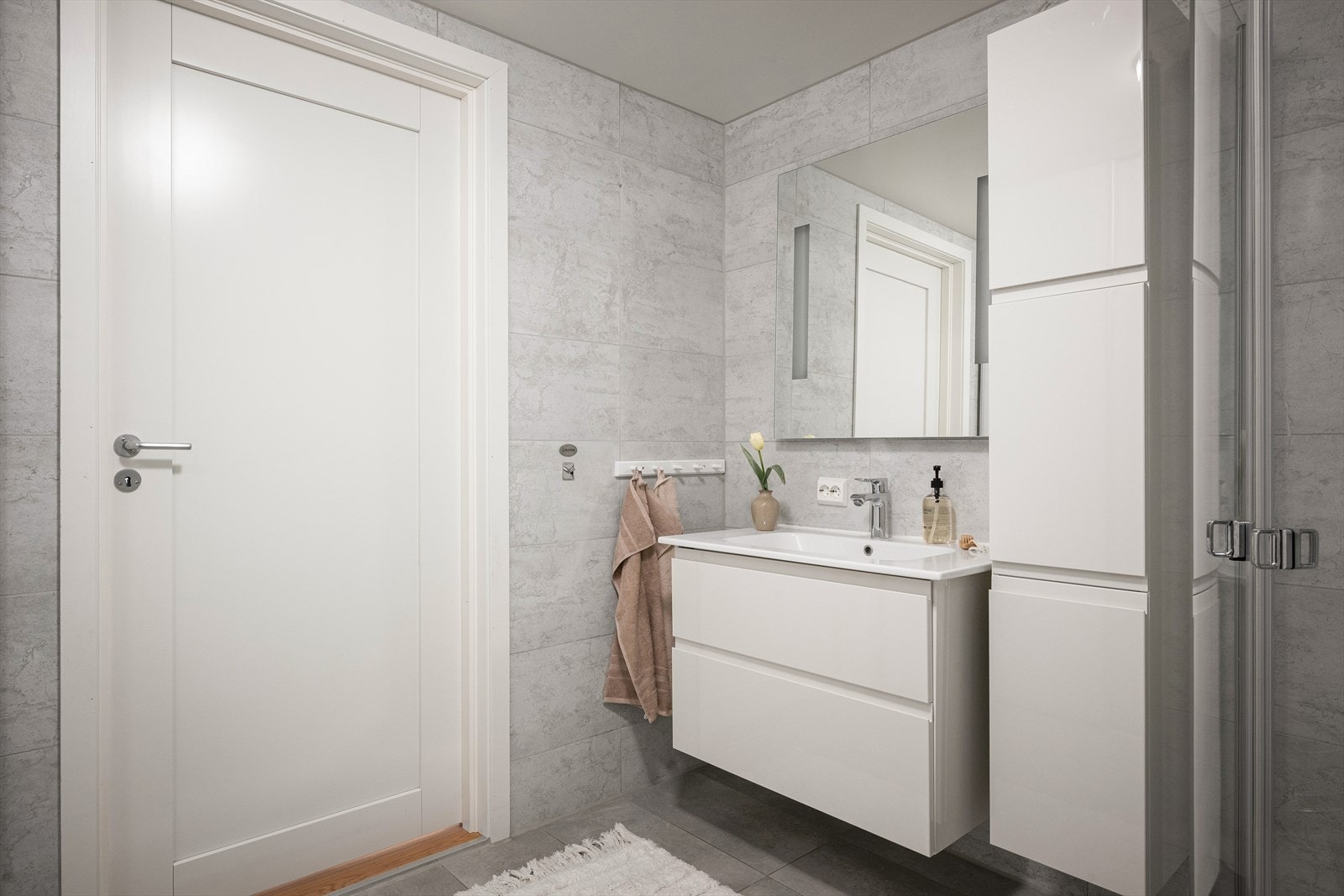Badet med fliser på gulvet (varme). Hvit seksjon, langskap og speil. Galleribilde