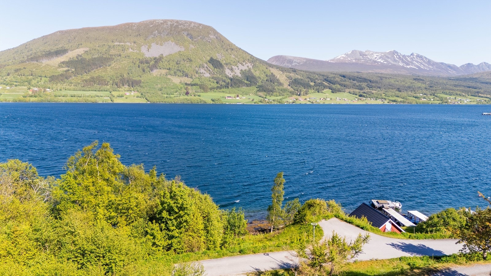 Utsikt fra medfølgende boligtomt over fjorden på en klar sommerdag. Infrastrukturen ligger fremført til tomten. Nausttomten ligger rett nedenfor tomten. Galleribilde