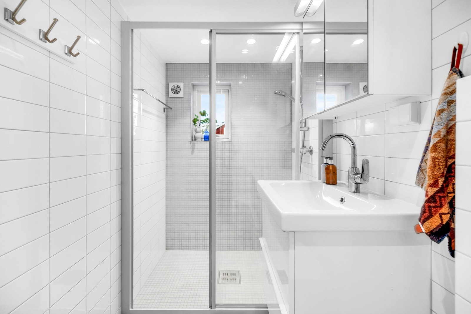 Badet er innredet med romslig dusj bak glassvegg og glassdør. Galleribilde