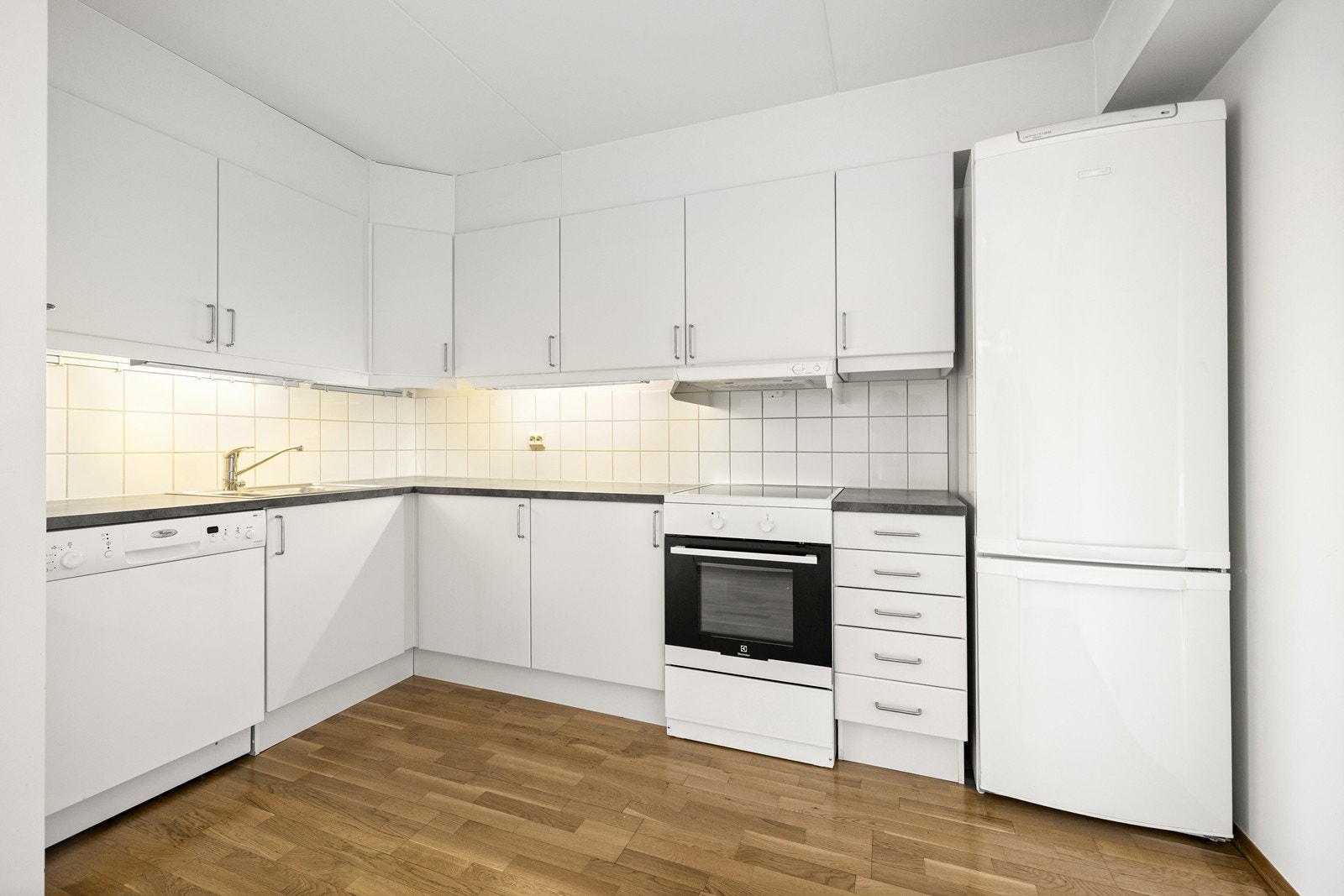Kjøkkeninnredning med glatte fronter, laminat benkeplate og fliser over benken. Galleribilde