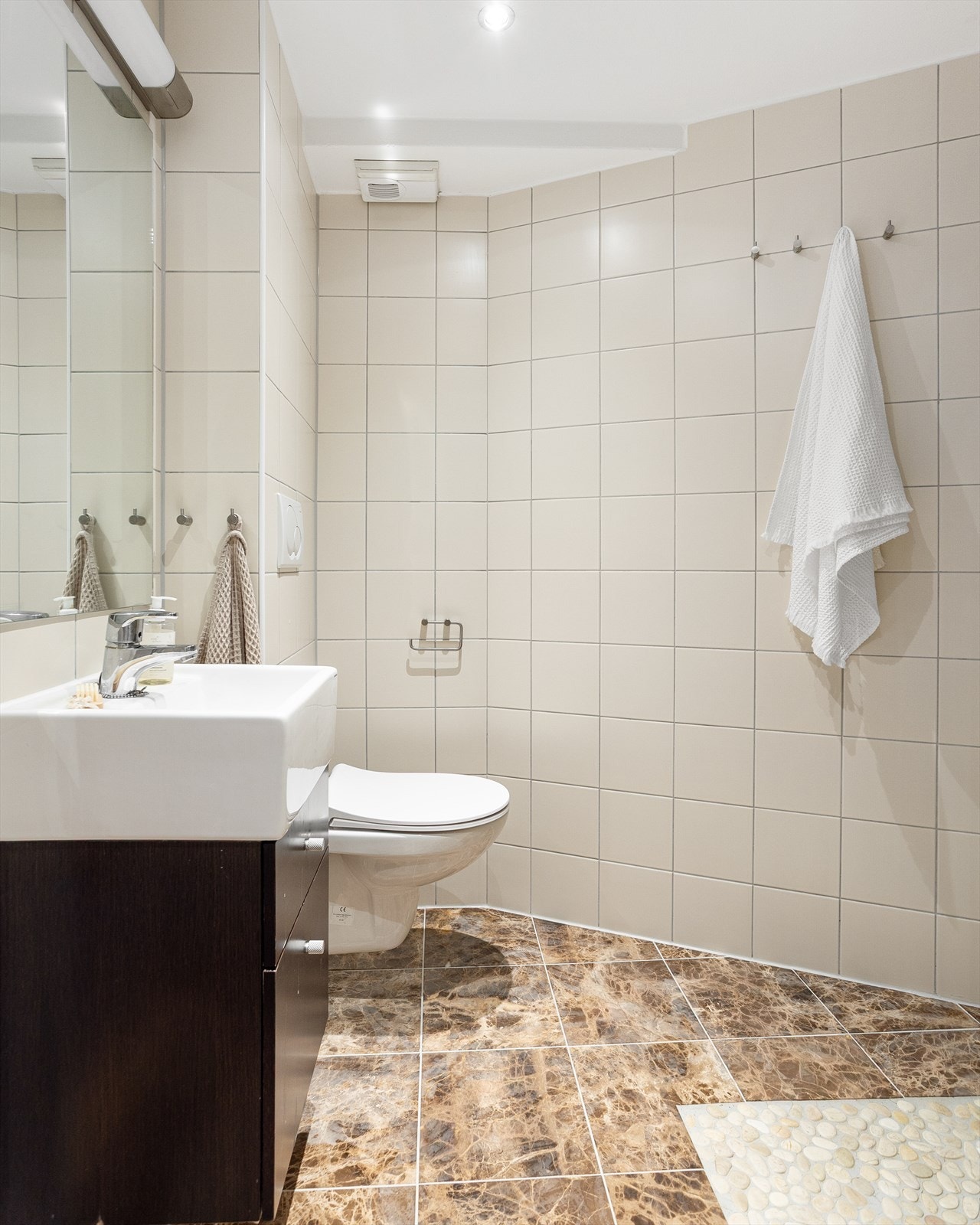 Badet er innredet med servantinnredning, veggmontert toalett, dusjhjørne og opplegg for vaskemaskin. Galleribilde