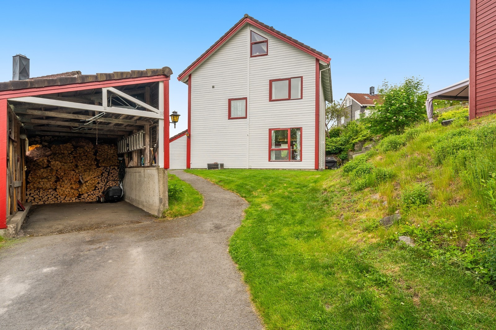 Eiendommen inkluderer en carport og en frittstående sportsbod for praktisk oppbevaring. Galleribilde