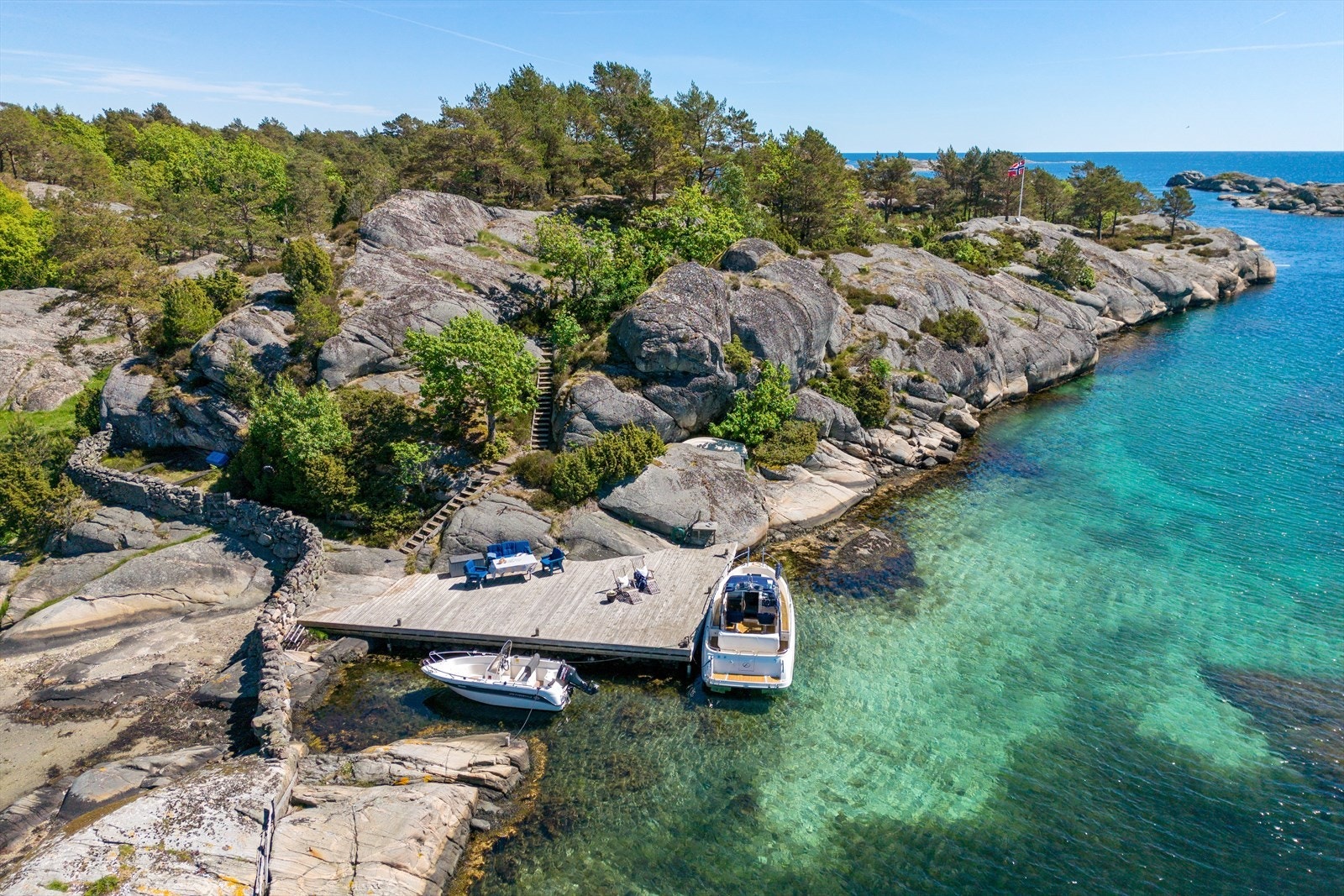 Den store brygga ligger skjermet til og tilbaketrukket fra båttraffikken i leia. Den er omkranset av fin sandbunn og har sol fra morgen til sen kveld.. Galleribilde