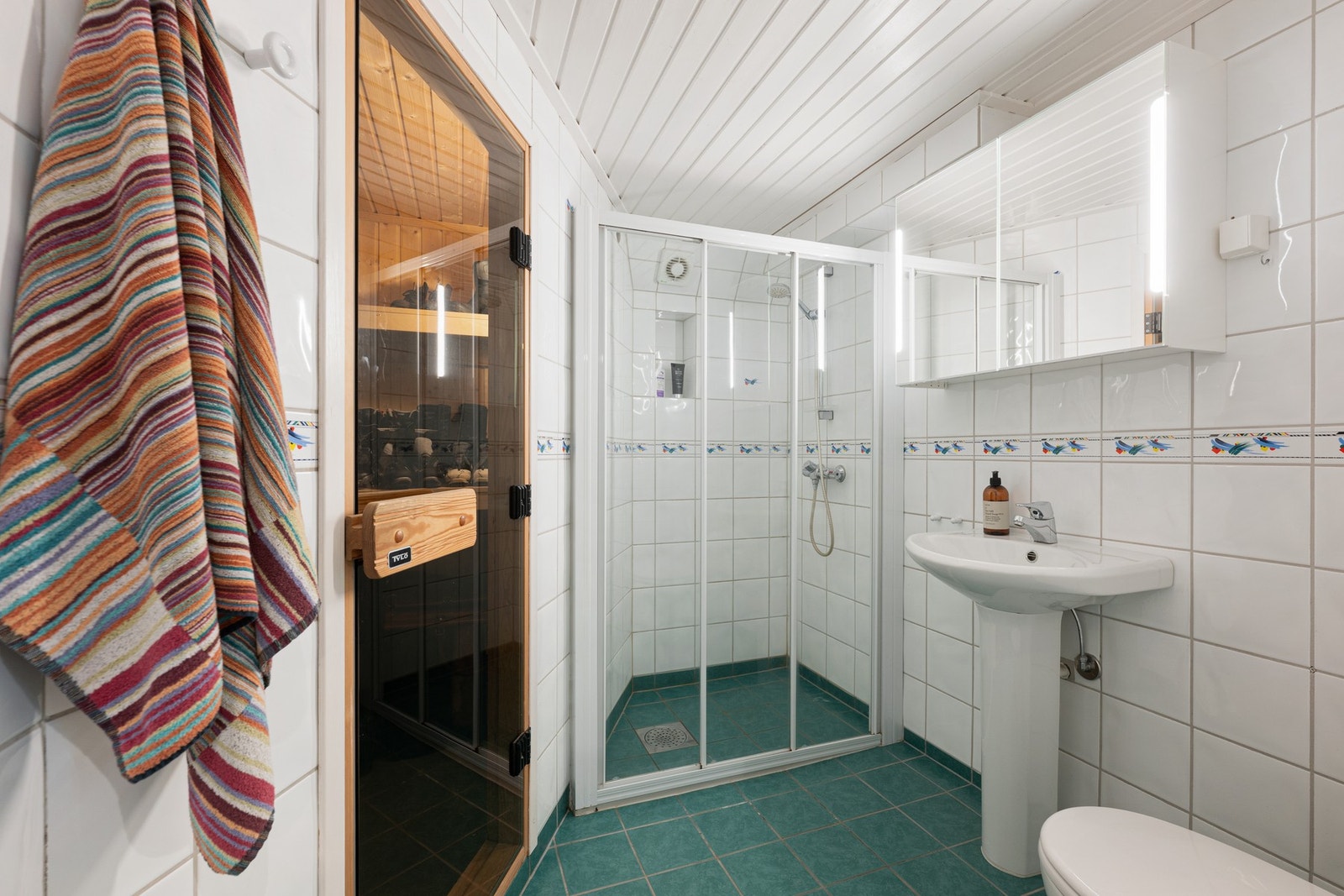Badet i underetasjen er flislagt og innredet med dusjhjørne, servant, speilskap og toalett. Galleribilde
