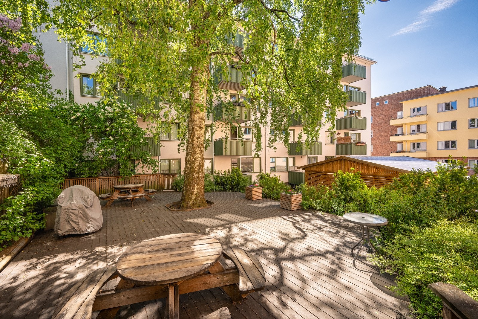 Frodig bakgård med hyggelige sittegrupper og grill Galleribilde