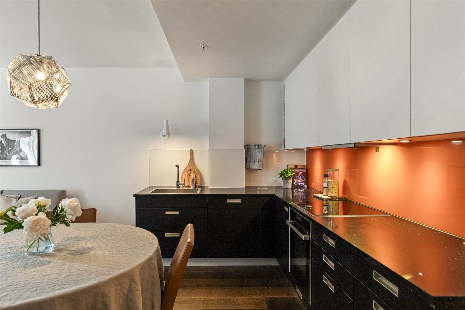 Kjøkkenet er fint plassert i en L-vinkel og har en mørk og moderne innredning med lyse overskap som gir en fin kontrast og som kler boligen godt. 2x3 stikkontakter er skjult under lokk i hhv benk og/eller overskap. Galleribilde