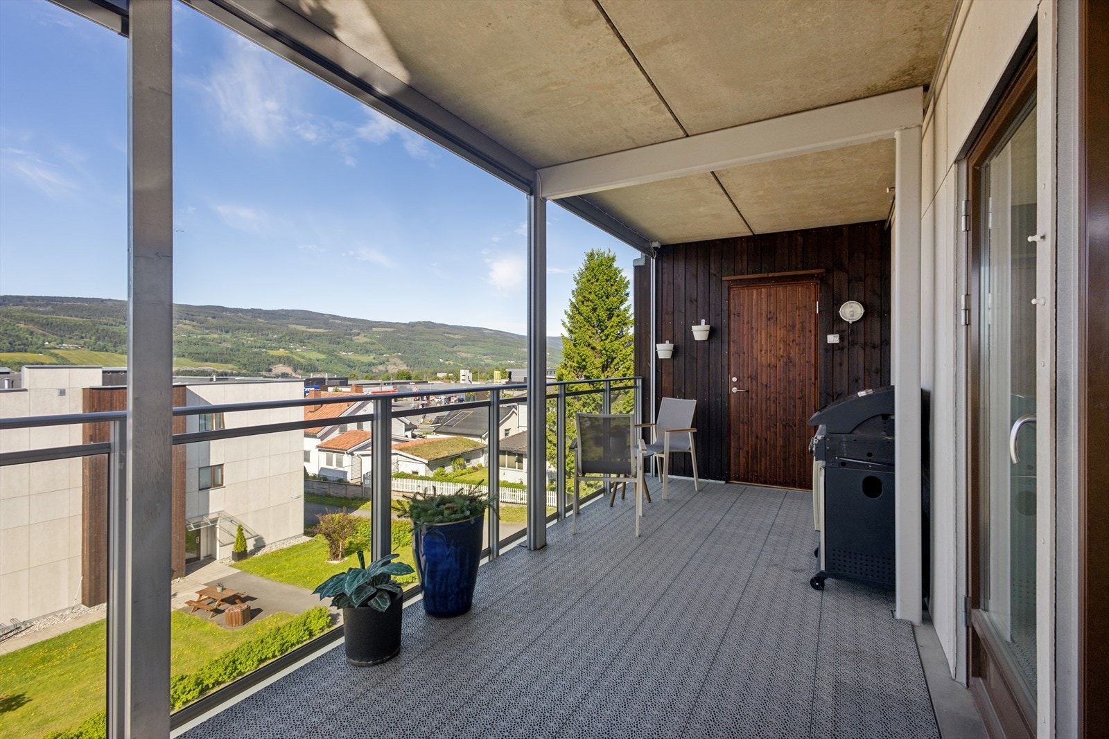 Verandaen har betongdekke med plastheller og rekkverk i glass. Galleribilde