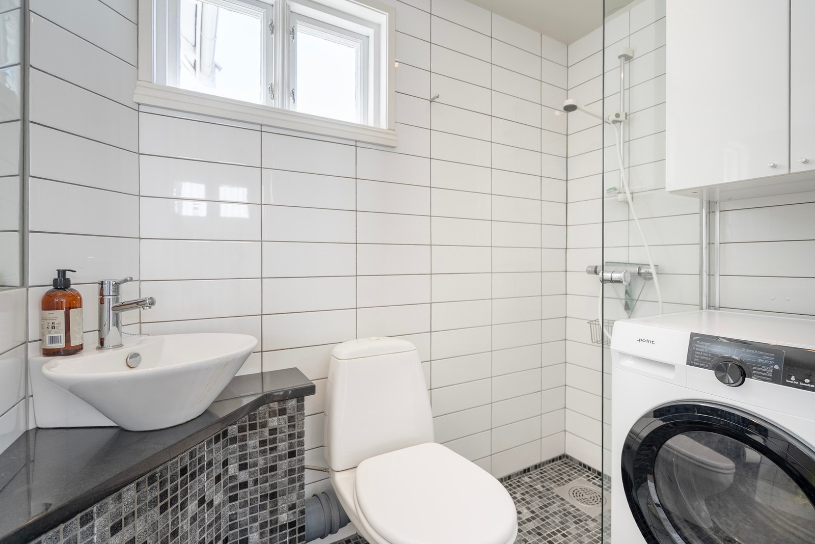 Badet i etasjen er arealeffektivt og godt utnyttet med dusj, toalett, servant, oppbevaring og opplegg for vaskemaskin Galleribilde