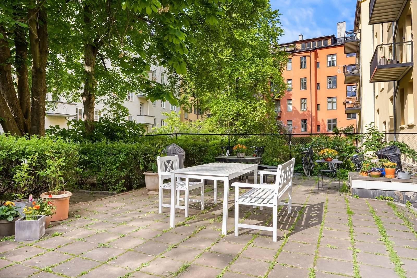 Bakgården er skjermet og omkranset av grønne trær med sittegrupper. Galleribilde