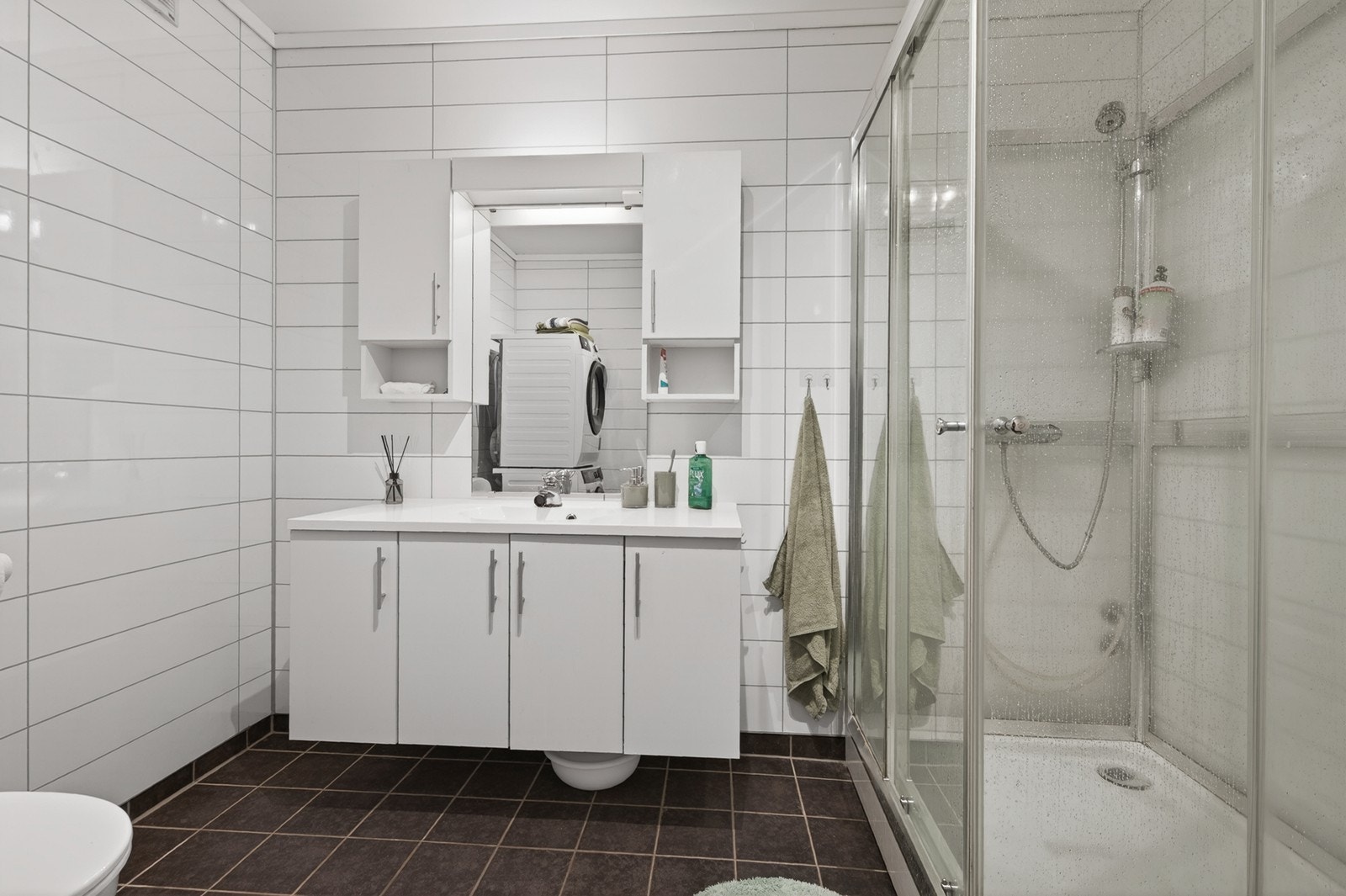 Kombinert bad/ vaskerom med stilren innredning og dusjkabinett Galleribilde